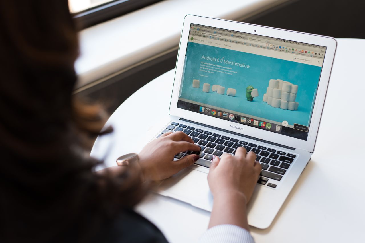 team-03 Businesswoman working on laptop with Android 6.0 Marshmallow webpage open.